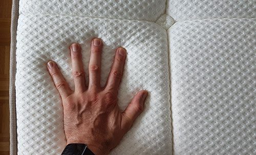 hand pushing into the dreamcloud mattress to demonstrate the density