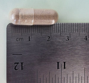 photo of a remrise pill next to a ruler showing it is 2cm long